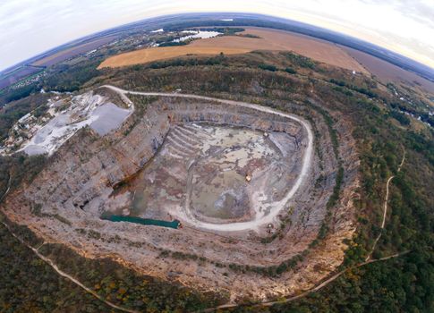 Aerial drone view of career in Europe at summer sunset, crushed stone quarry, beautiful nature round, some excavators, diggers inside