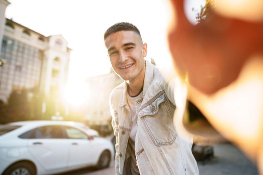 Portrait of young man taking a selfie while out on the city street, close up selfie