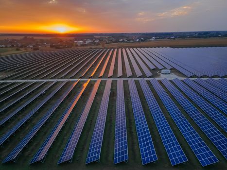 Aerial drone view of large solar panels at a solar farm at bright summer sunset. Solar cell power plants, colorful photo