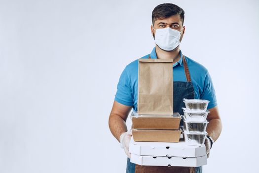 Delivery man in protective mask and medical gloves holding takeaway food. Compliance with the hygiene rules while covid-19 pandemic. Safe service