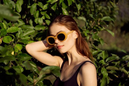 pretty woman in black swimsuit sunglasses green leaves nature. High quality photo