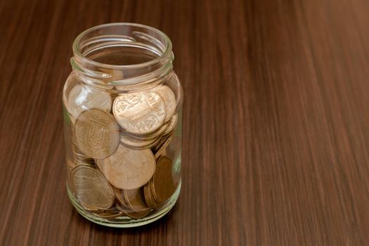 Ukrainian golden coins in a glass jar on dark background