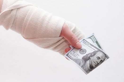 female hand rewound with a bandage holds a dollar bill money white background 100 dollars