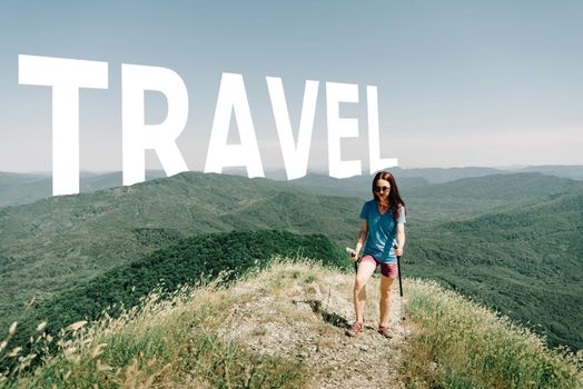 Sporty woman walking with trekking poles along the ridge of a mountain in summer. Word travel in blue sky.