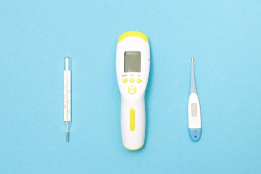 three thermometers on a blue background, electronic, mercury and infrared thermometers for measuring body temperature