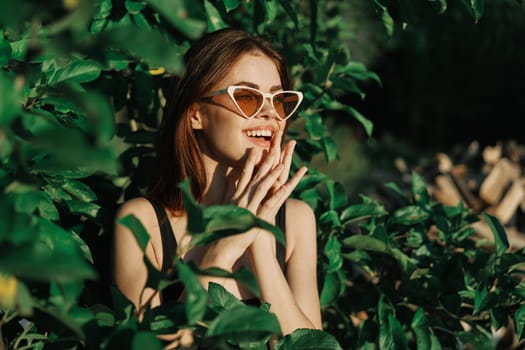 smiling woman wearing sunglasses green leaves nature fashion. High quality photo