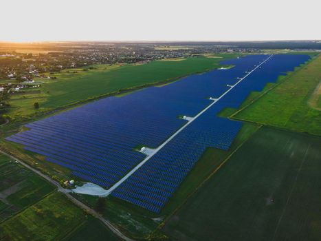 Aerial drone view of large solar panels at a solar farm at bright summer sunset. Solar cell power plants, colorful photo