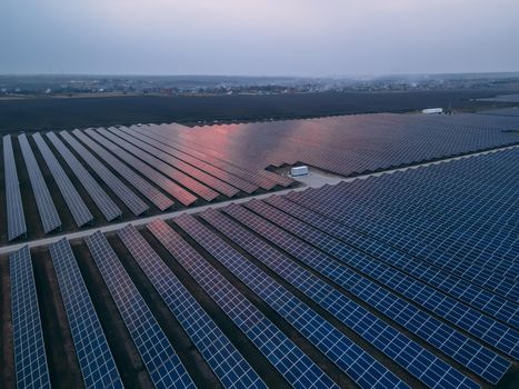 Aerial drone view of large solar panels at a solar farm at bright spring sunset. Solar cell power plants, colorful HDR photo