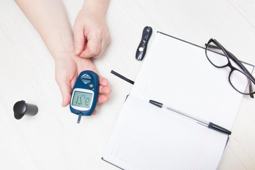 woman measures blood sugar glucose meter, diabetes concept, notebook for writing and monitoring