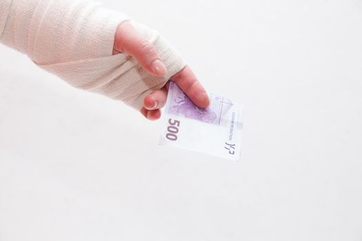bandaged female hand holds a 500 euro bill