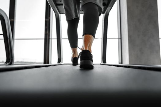 Close up photo of male legs running in a gym on a treadmill