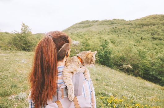 Young woman walking with a cat on nature in summer.