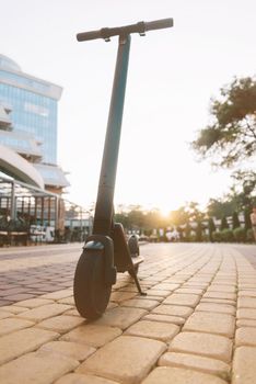 Ecological modern electric scooter in city street in summer at sunset, no people.