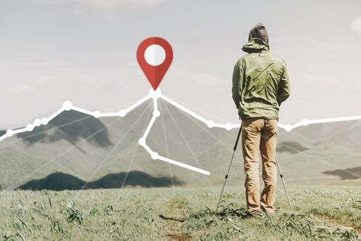 Explorer young man with trekking poles standing in front of scheme of route with location GPS pin on peak of mountain in summer outdoor.