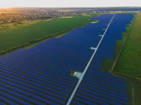 Aerial drone view of large solar panels at a solar farm at bright summer sunset. Solar cell power plants, colorful photo