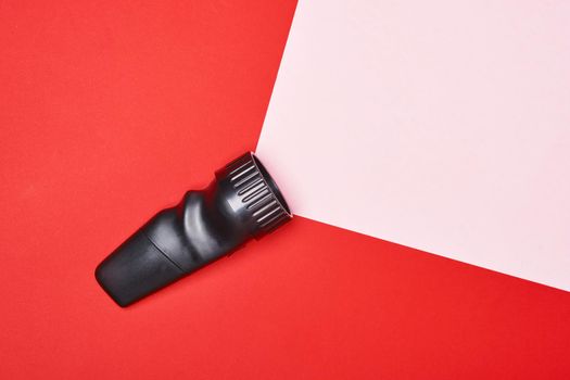 Flashlight on a red background with a pink ray of light, made from paper copy space. top view