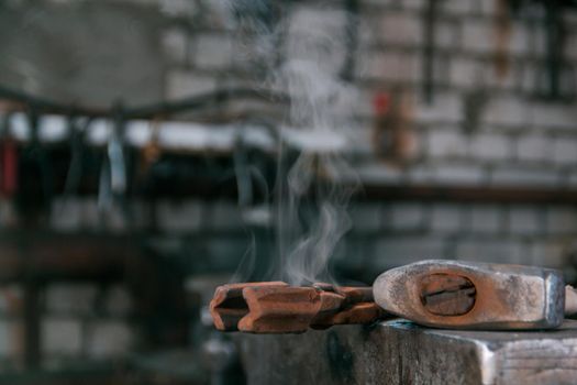 steam comes from the tool lies on anvil at forge. Close up shot