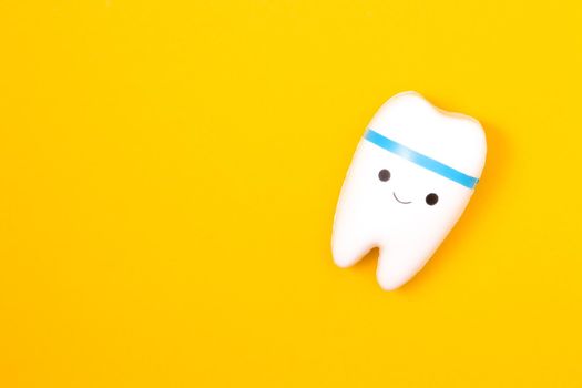 tooth model on a yellow background, happy tooth, smilling tooth, white healthy tooth, copy space, oral care concept