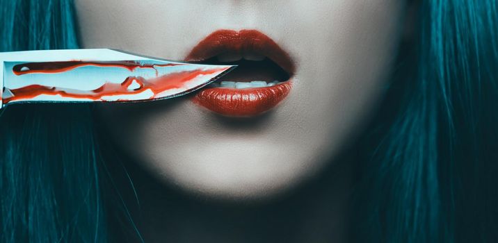 Knife in blood near red lips of woman, close-up. Horror and Halloween concept.