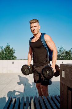 sporty man in the park with dumbbells workout fitness. High quality photo