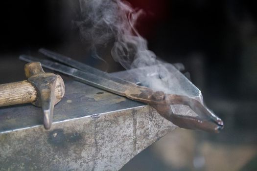 steam comes from the different tools lies on anvil. Close up shot
