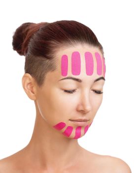 Beautiful young woman with vertical kinesio tapes on her forehead and chin for facelift. Beauty concept.