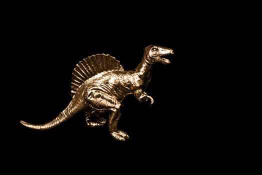 Golden toy dinosaur isolated on black background. Pop art concept.