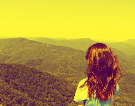 Traveler young woman looking at mountains outdoor. Image with retro vintage color effect.