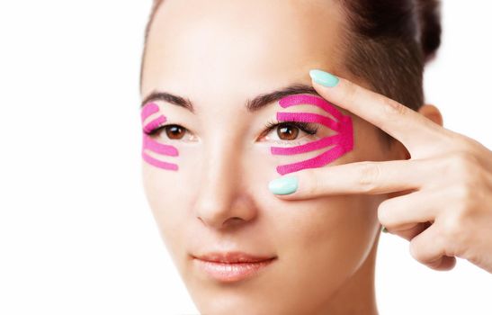 Beautiful young woman with kinesiology tape on eyelid, facelift beauty procedure.