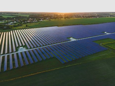 Aerial drone view of large solar panels at a solar farm at bright summer sunset. Solar cell power plants, colorful photo