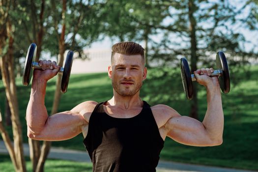 pumped up sports Vykhino in the park with dumbbell workout. High quality photo