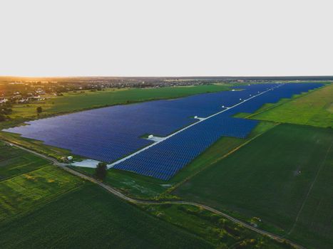 Aerial drone view of large solar panels at a solar farm at bright summer sunset. Solar cell power plants, colorful photo