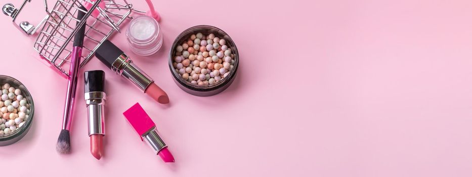 Creative concept with shopping trolley with makeup on a pink background.