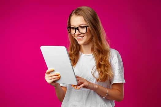 Attractive young woman using white digital tablet against pink background