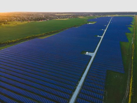 Aerial drone view of large solar panels at a solar farm at bright summer sunset. Solar cell power plants, colorful photo