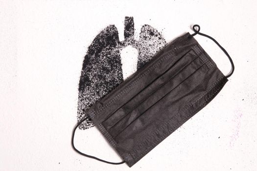 silhouette of human lungs from coal dust on a white background, lungs from pieces of coal and a black face mask, lung and respiratory diseases concept