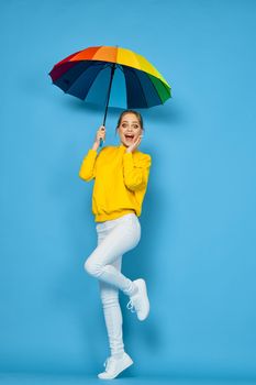 woman with multicolored umbrella in yellow sweater posing rainbow colors. High quality photo