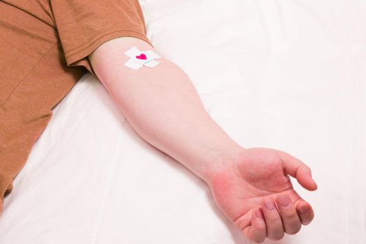 male hand with patch glued with a cross, heart on a patch, blood donor concept