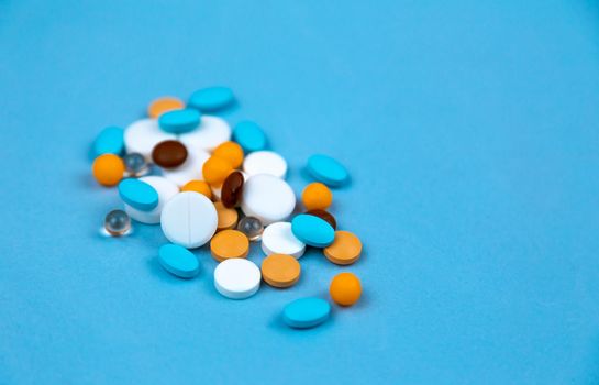 Multi-colored pills on a blue background close-up, with copy space for text.