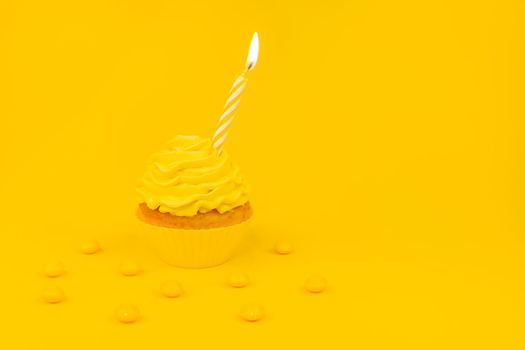 Tasty cupcake with birning candle on a yellow background. Monochrome birthday concept banner with cupcake and yellow frosting and yellow candy. Copy space.