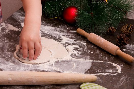 little girl's hand makes christmas cookies, christmas background, bright colors, red christmas tree decorations, copy space