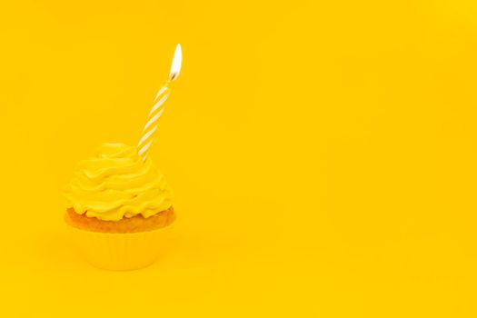 Tasty cupcake with birning candle on a yellow background. Monochrome birthday concept with cupcake and yellow cream. Copy space.