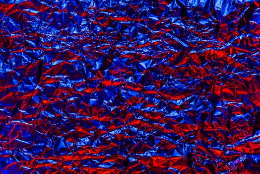 Red and blue foil background with shiny crumpled surface for texture background. Iridescent surface wrinkled foil.