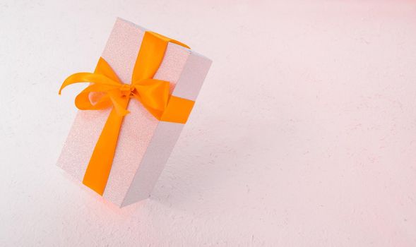 falling shiny gift box on a light background with a gold bow