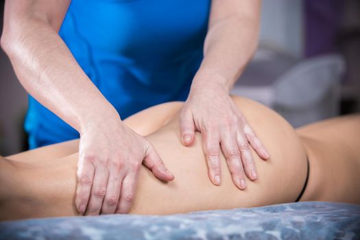 Massage session. A woman giving an anticellulite massage treatment. Thighs massage. Close up