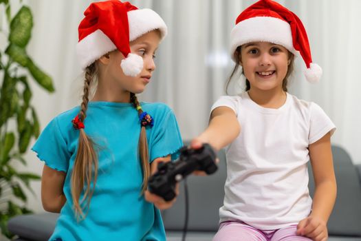 Happy children, two little girls with a joystick playing a video game