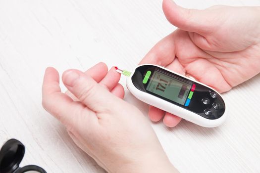 a diabetic measures blood sugar with a glucose meter, a diabetes concept, a drop of blood on his finger, a blood test