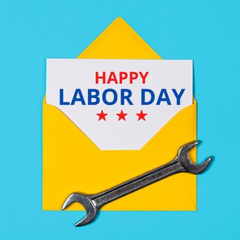 Happy labor day concept. Yellow Envelope and wrench on blue background