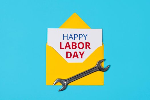 Happy labor day concept. Yellow Envelope and wrench on blue background