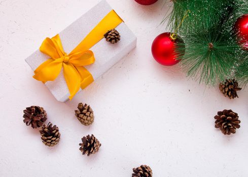 gift box with golden bow on a white background with pine branch and cones